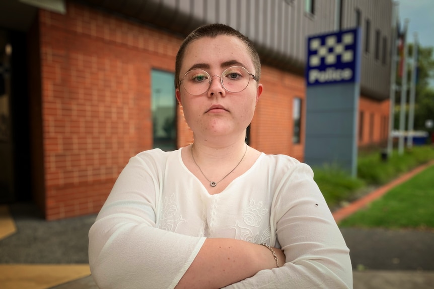 Nadia Bach in front of a police station with arms folded.