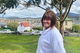 A woman wearing a jumper smiles at the camera, with Hobart visible in the background.