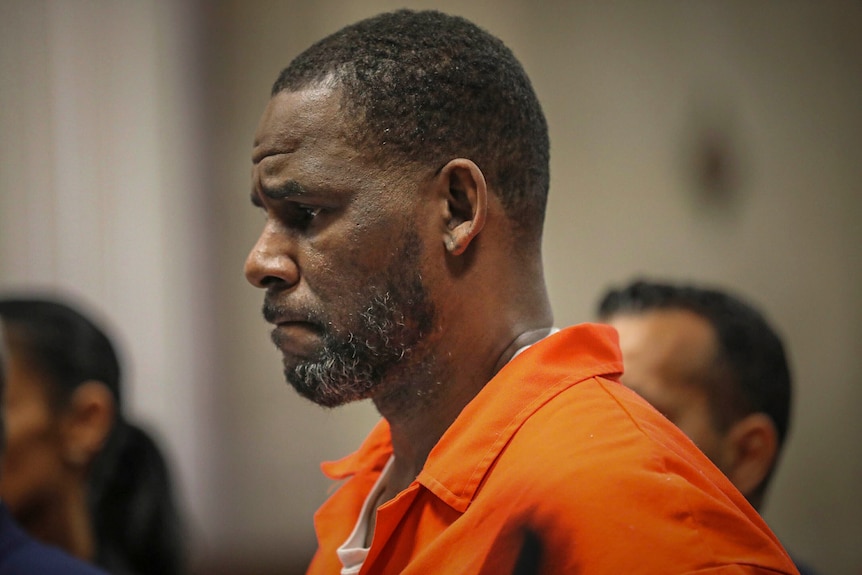 R kelly looking down whle in orange jumpsuit in court