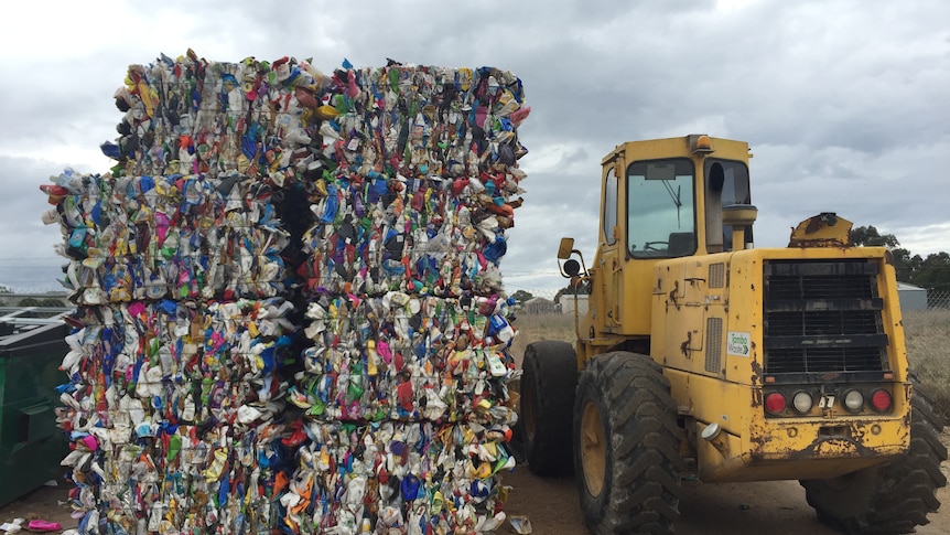 Bales of plastic waste next to a bobcat vehicle