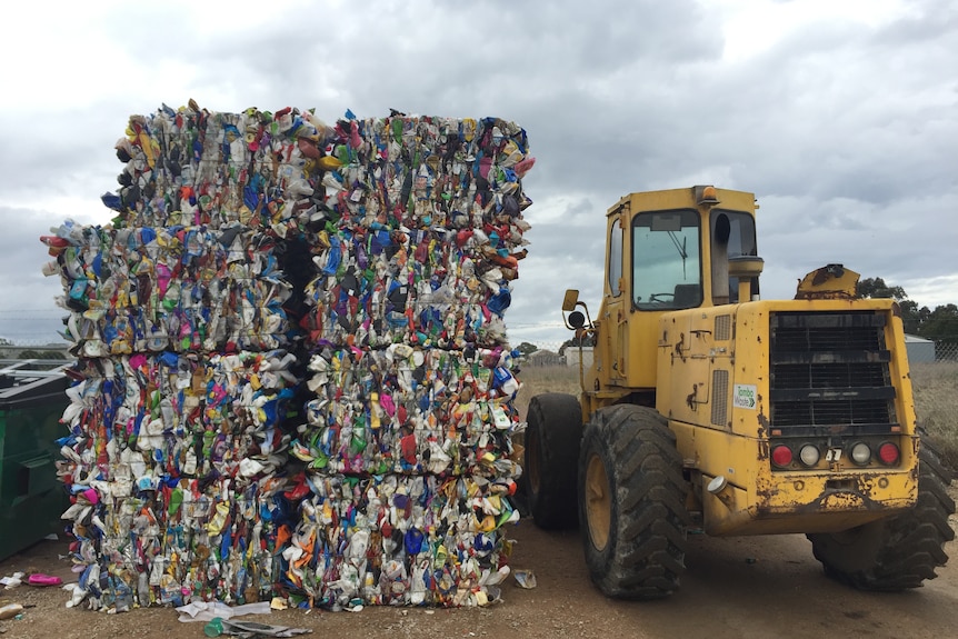 Bales of plastic waste next to a bobcat vehicle