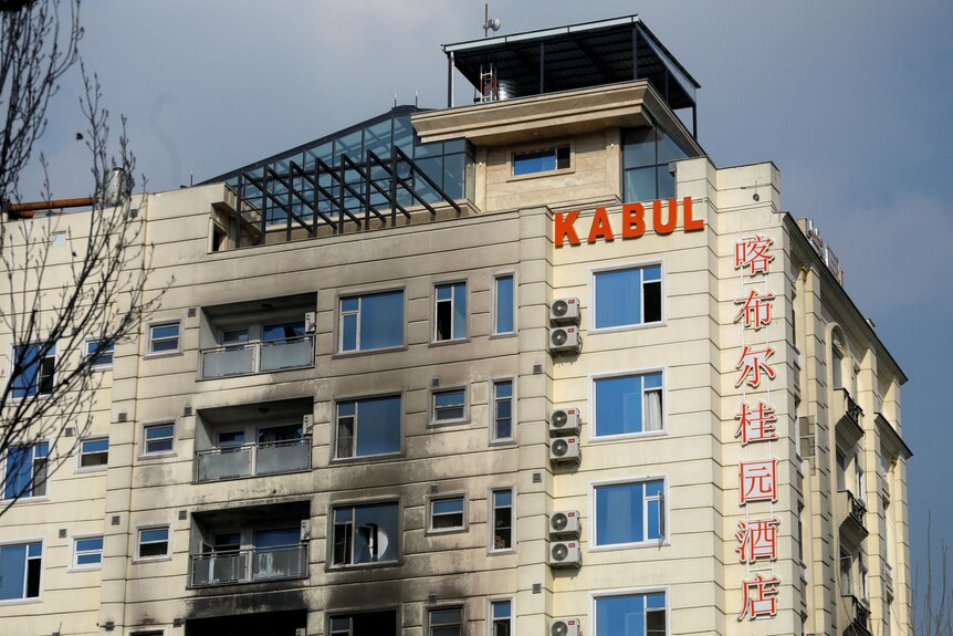 The outside of a building with KABUL sign shows several floors blackened and windows damaged