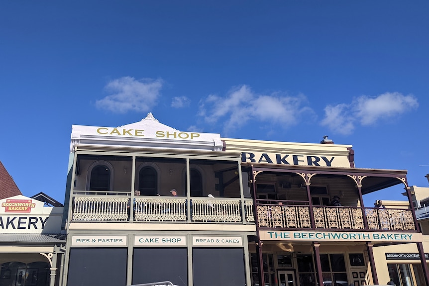 The outside view of a historic shop front with an ornate balcony, that says Cake Shop and Bakery in big letters 