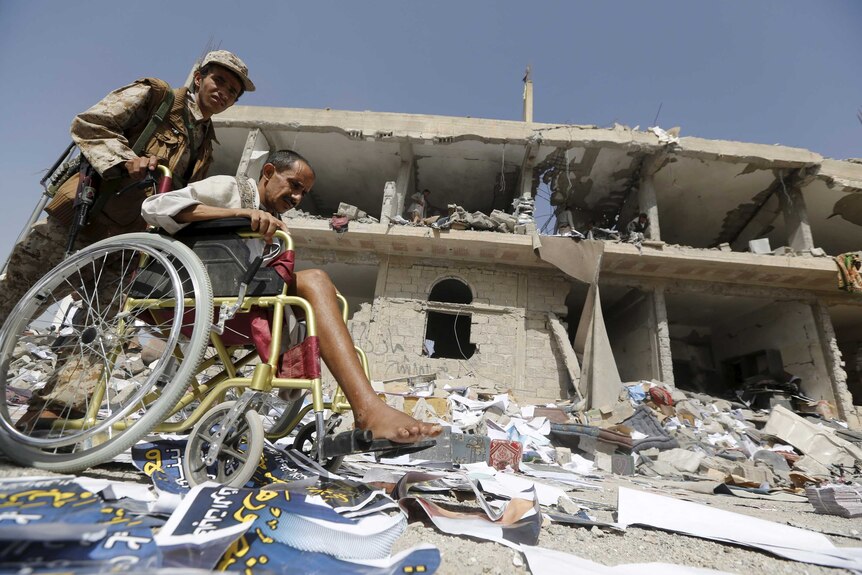 Houthi militant passes damaged buildings