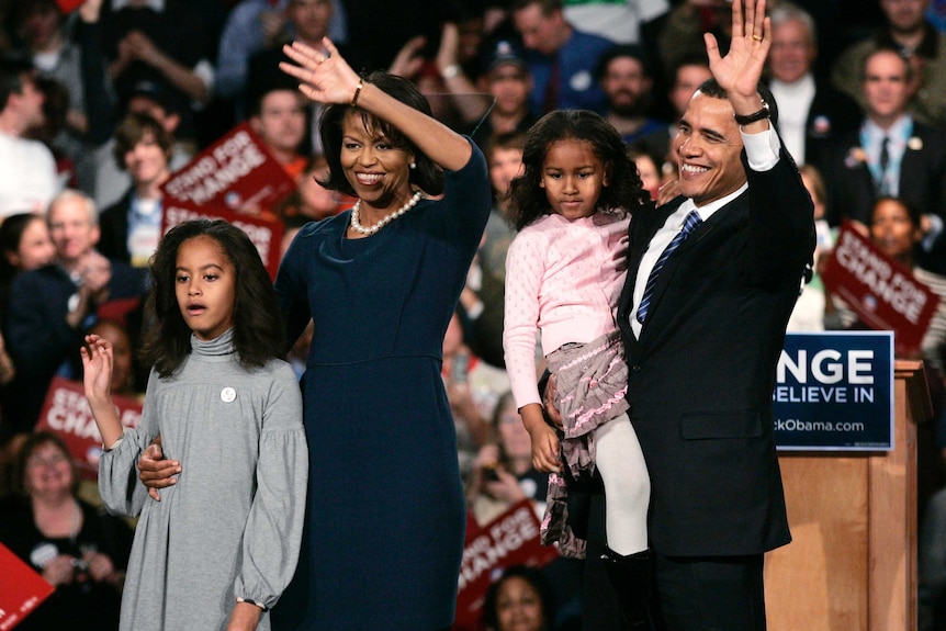 Barack Obama with Michelle and the girls waving to supporters from a stage