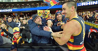 Taylor Walker of the Crows celebrates with fans in the crowd after a match against Geelong.