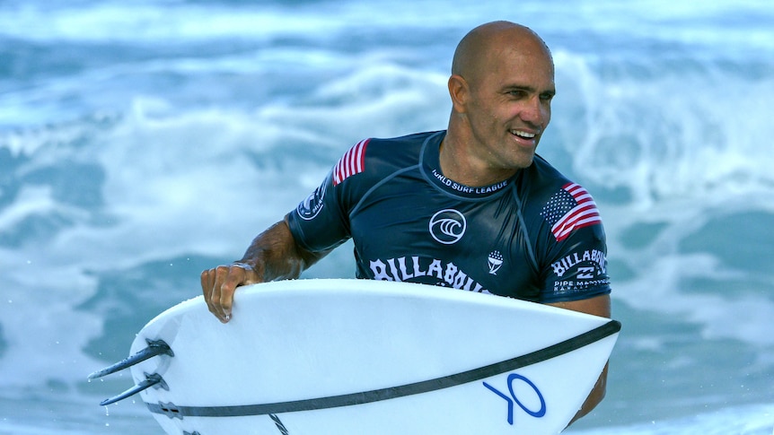 Kelly Slater with his surf board in his hands while coming out of the ocean