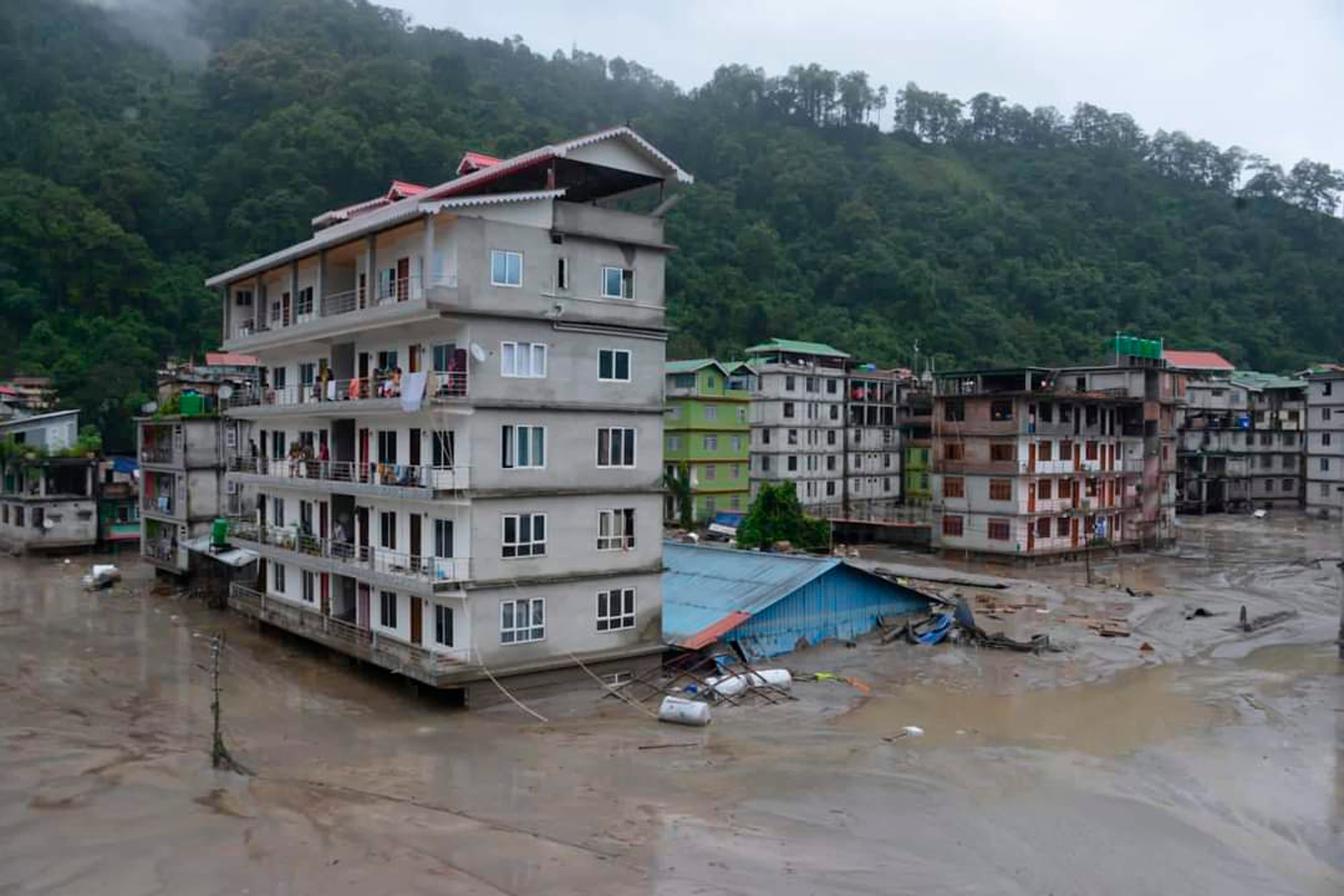 Five story buildings in an India village are flooded with dirty brown water.