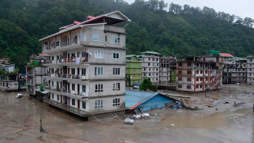 Five story buildings in an India village are flooded with dirty brown water.