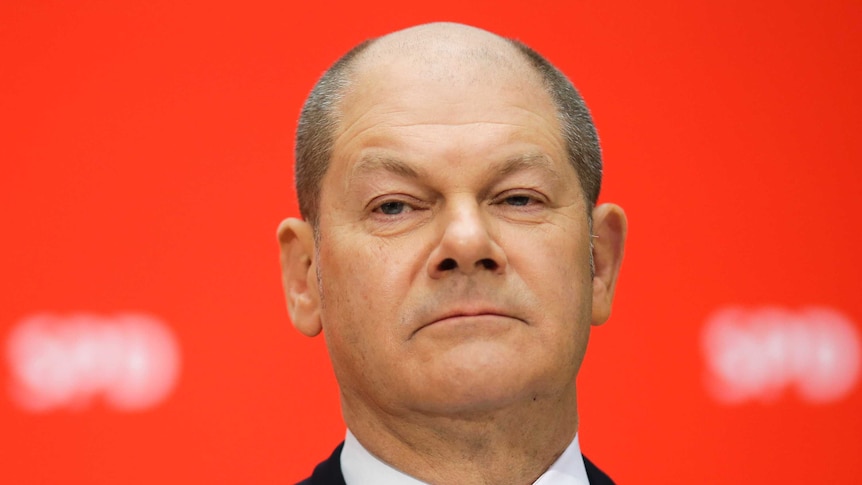 German Social Democratic Party's Olaf Scholz stands in front of red backdrop