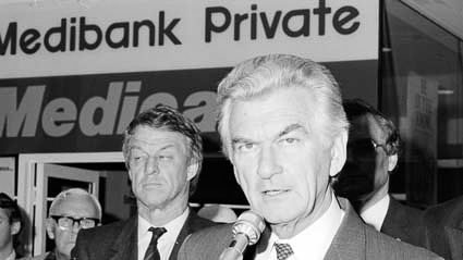 A black and white image of Bob Hawke at a microphone.