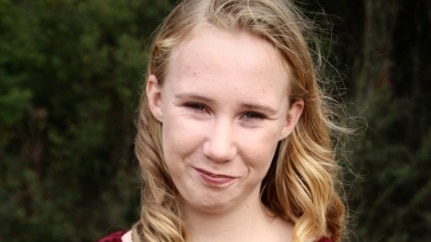 A young blonde girl smiles at the camera