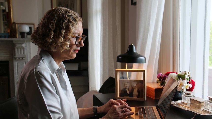 Joanna Murray-Smith working on a laptop at a desk by a large window.