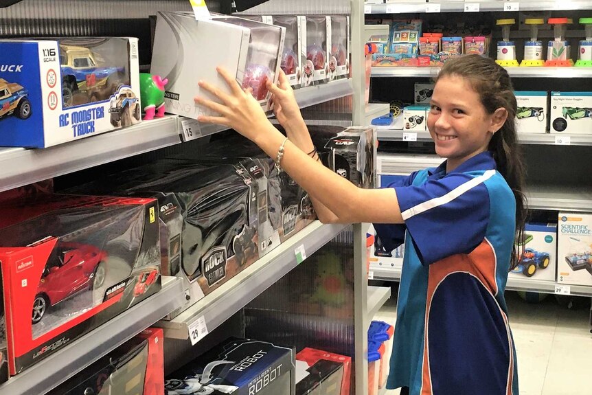 Madeline MacDonald in a store reaching for a boy's gift off a shelf to gift in the SVDP ABCD appeal