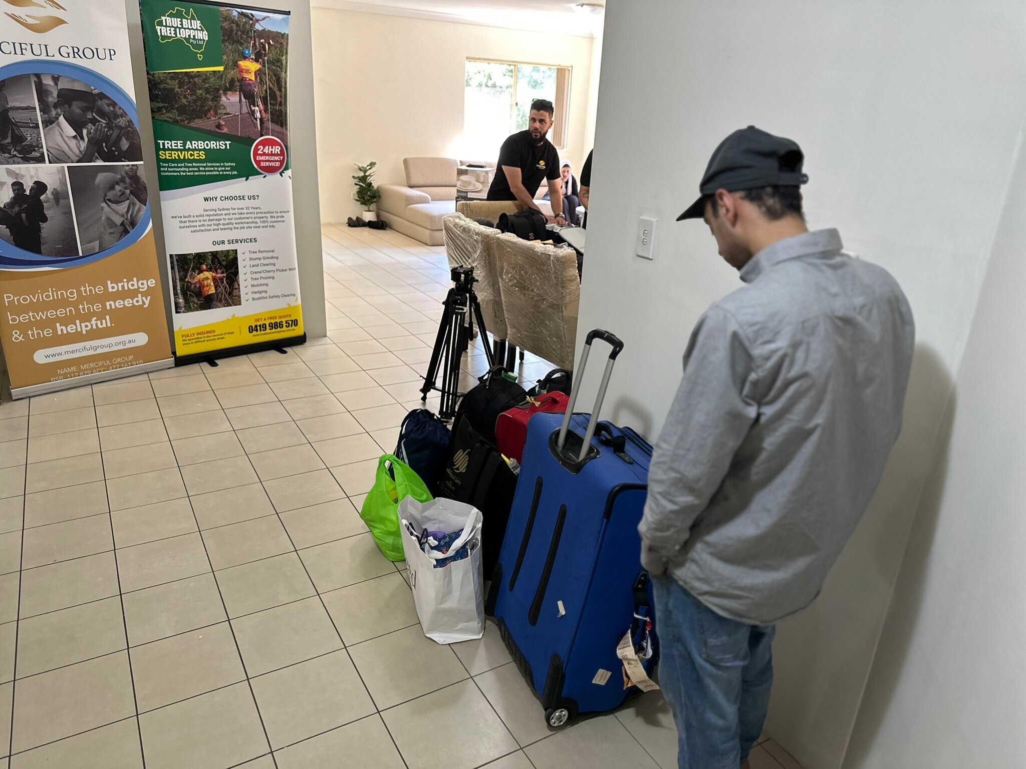 Um Ali's son is at the door of the apartment with luggage in view.