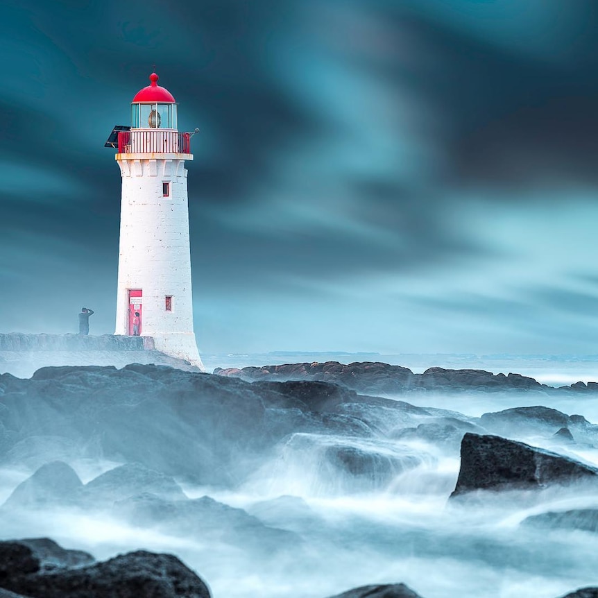 A storm rages around a lighthouse.