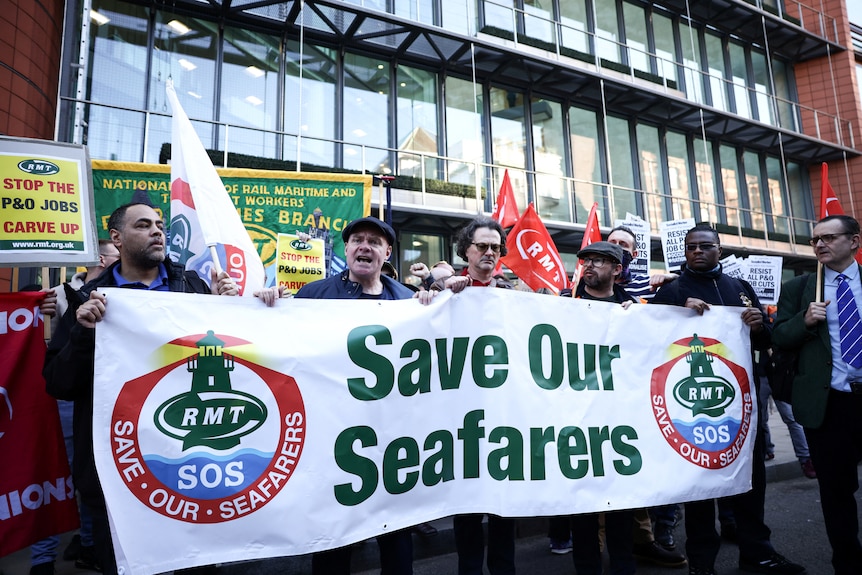 People hold large sign reading 'save our seafarers' 