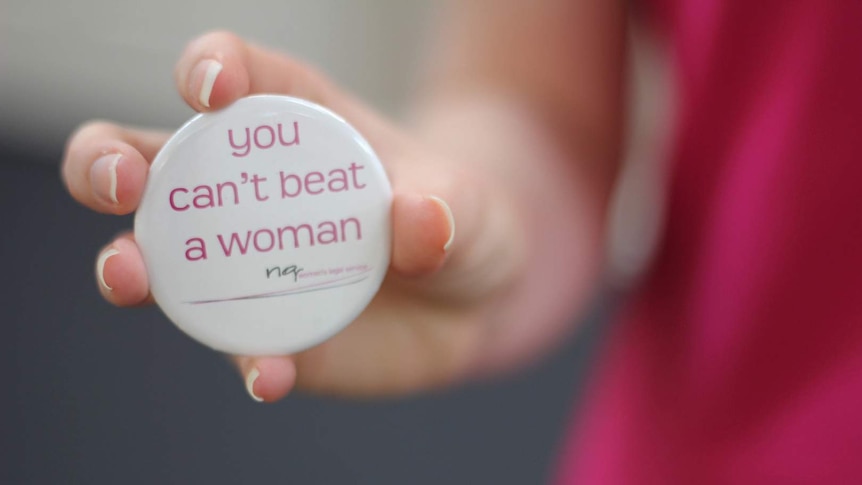 A woman's hand holds a badge reading 'You can't beat a woman'.