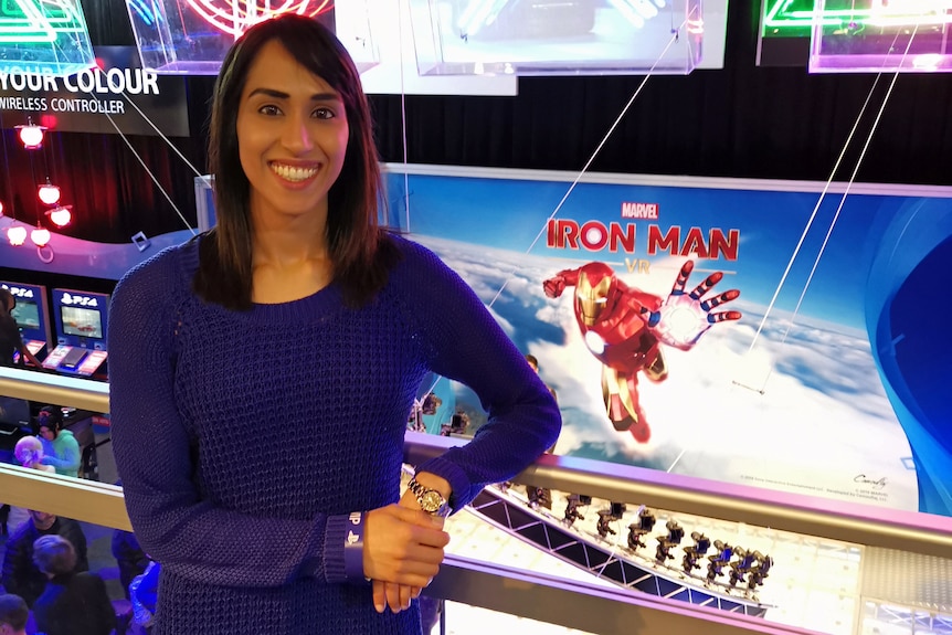 A woman standing in front of a gaming console and screen lit-up.