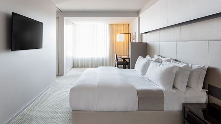 A modern hotel room with a bed and a television.