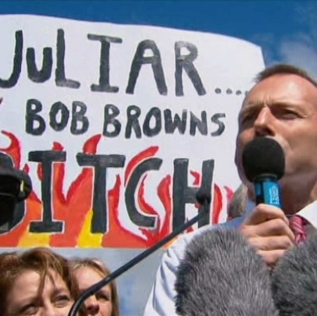 Tony Abbott stands in front of an offensive anti-Julia Gillard protest sign.