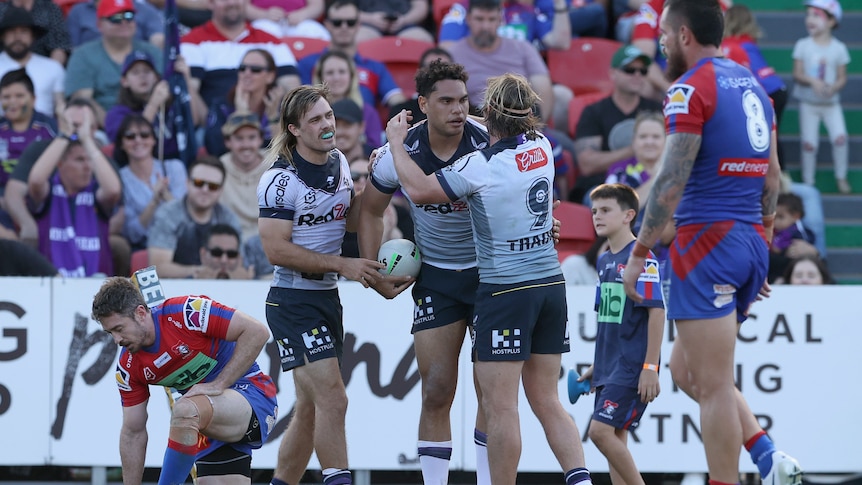Xavier Coates is embraced by Melbourne Storm teammates after a try against the Newcastle Knights.