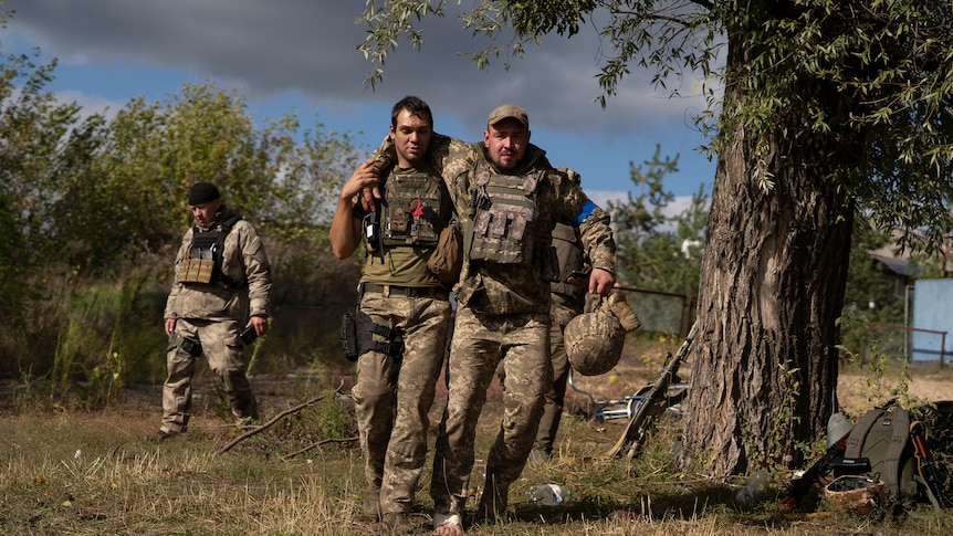 A Ukrainian serviceman helps a comrade during an evacuation of injured soldiers participating in the counteroffensive.