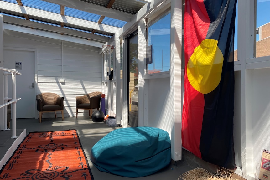 A sunny room with chairs, a beanbag and the Aboriginal flag. 