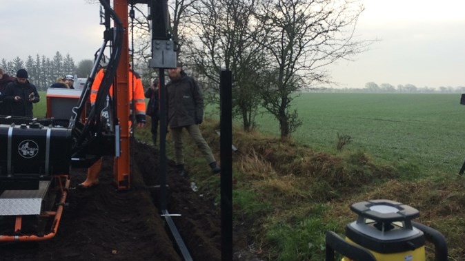 A misty photo in a green paddock of a fence with metal poles being built