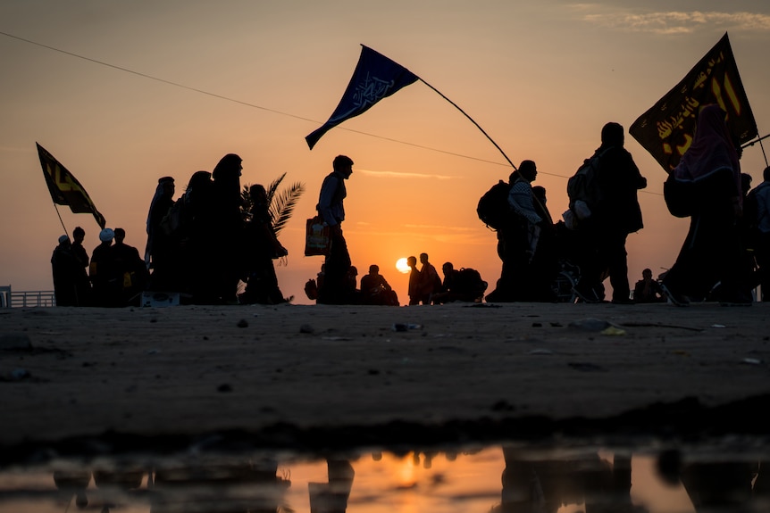 Silhouettes of crowded people walking at sunset time in Iraq.