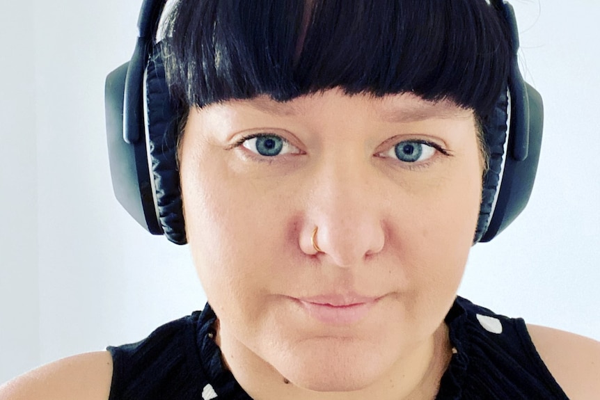 Woman stares at the camera wearing large over-ear headphones