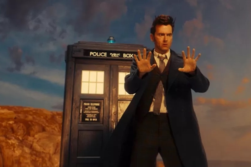 Actor David Tennant portraying The Doctor in Doctor Who, standing near a TARDIS and looking at the back of his hands.