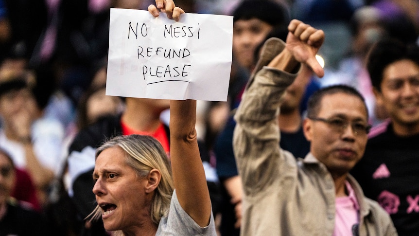 A fan holds up a sign saying no Messi refund please