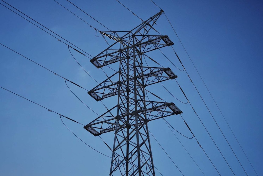 Angled close-up of high tension power lines and steel towers looking up towards a blue sky in Brisbane.