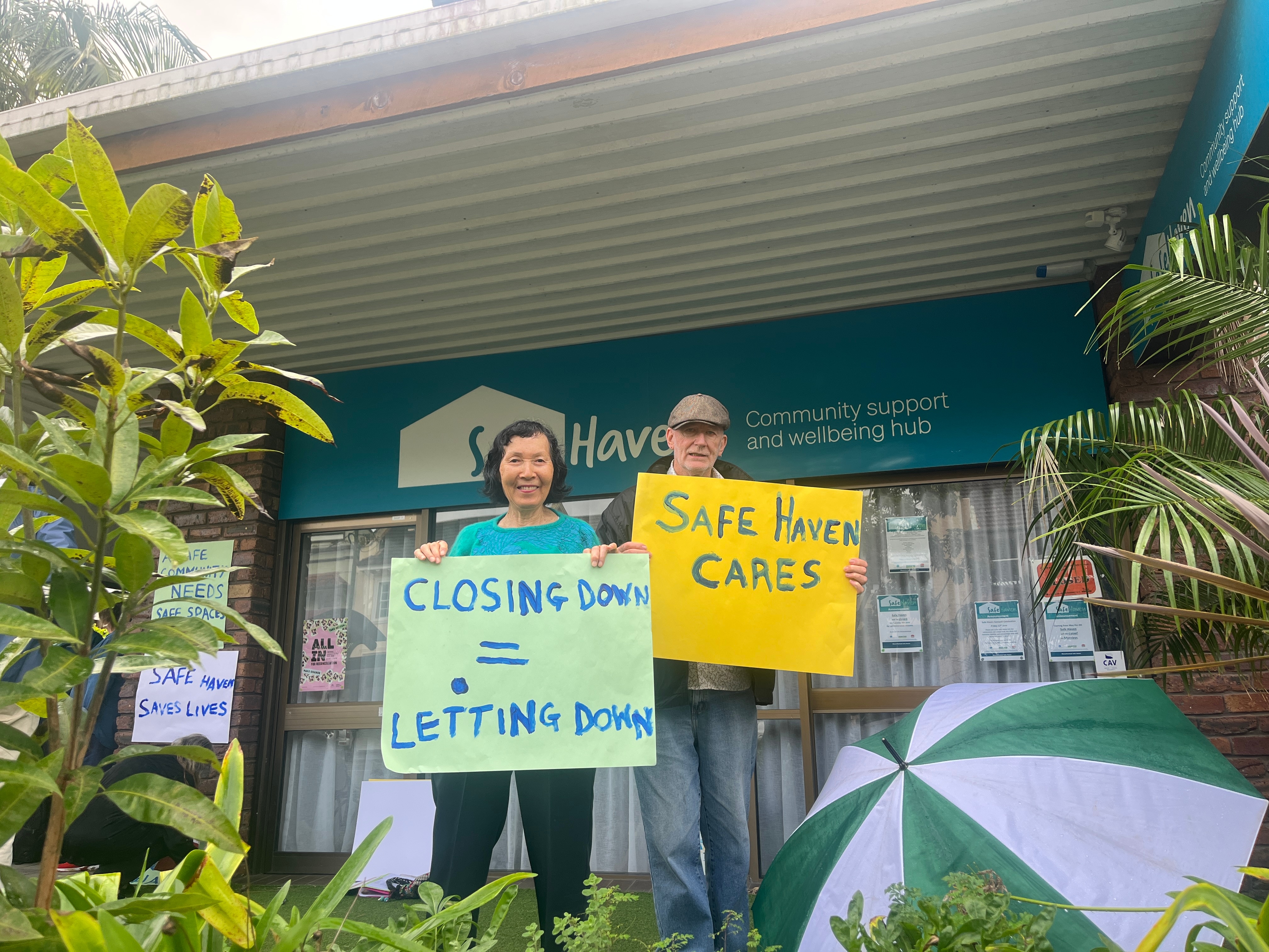 A man and a woman stand with sighs saying 'Safe Haven Cares' out side a pop up mental health centre in Murwillumbah NSW