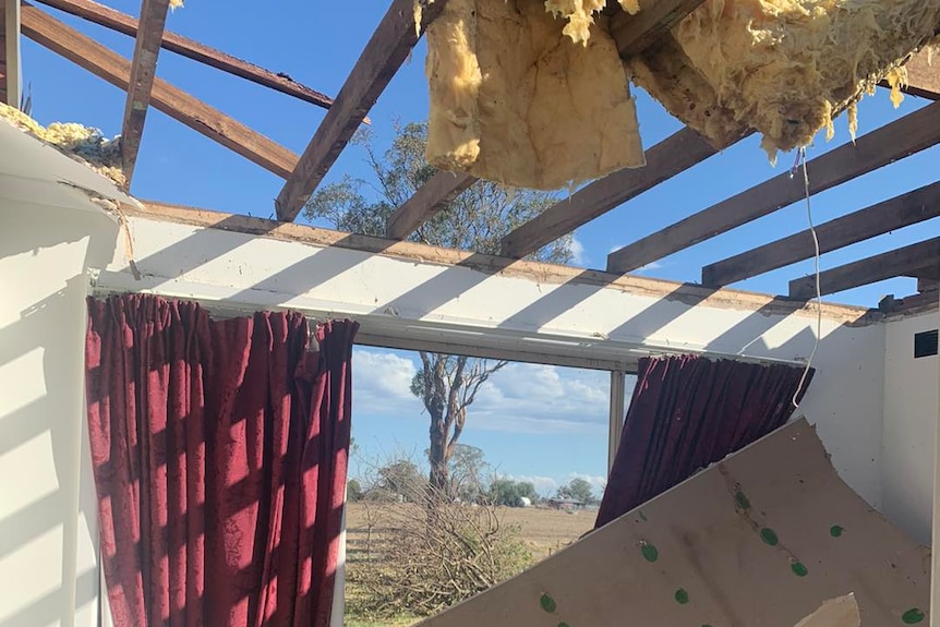 Curtains hang in front of a glassless window in a house with no roof.