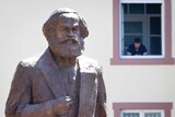 People take photos on mobile phones of a bronze statue of German philosopher Karl Marx