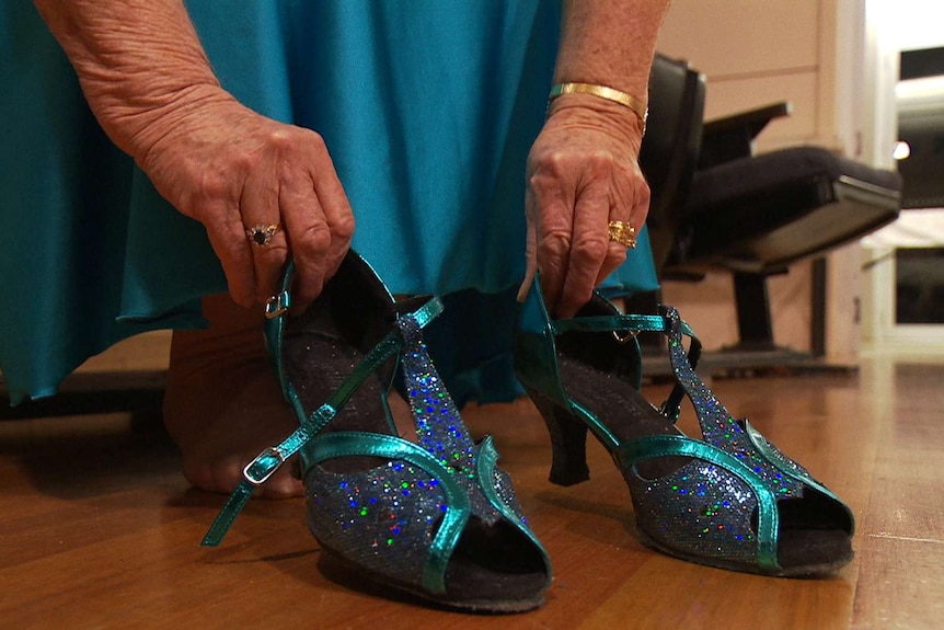 A woman sits with a pair of blue dancing shoes.