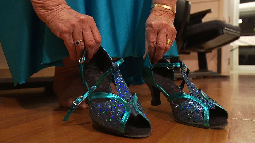 A woman sits with a pair of blue dancing shoes.
