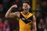 A Hawthorn AFL players pumps his right fist as he celebrates a goal.