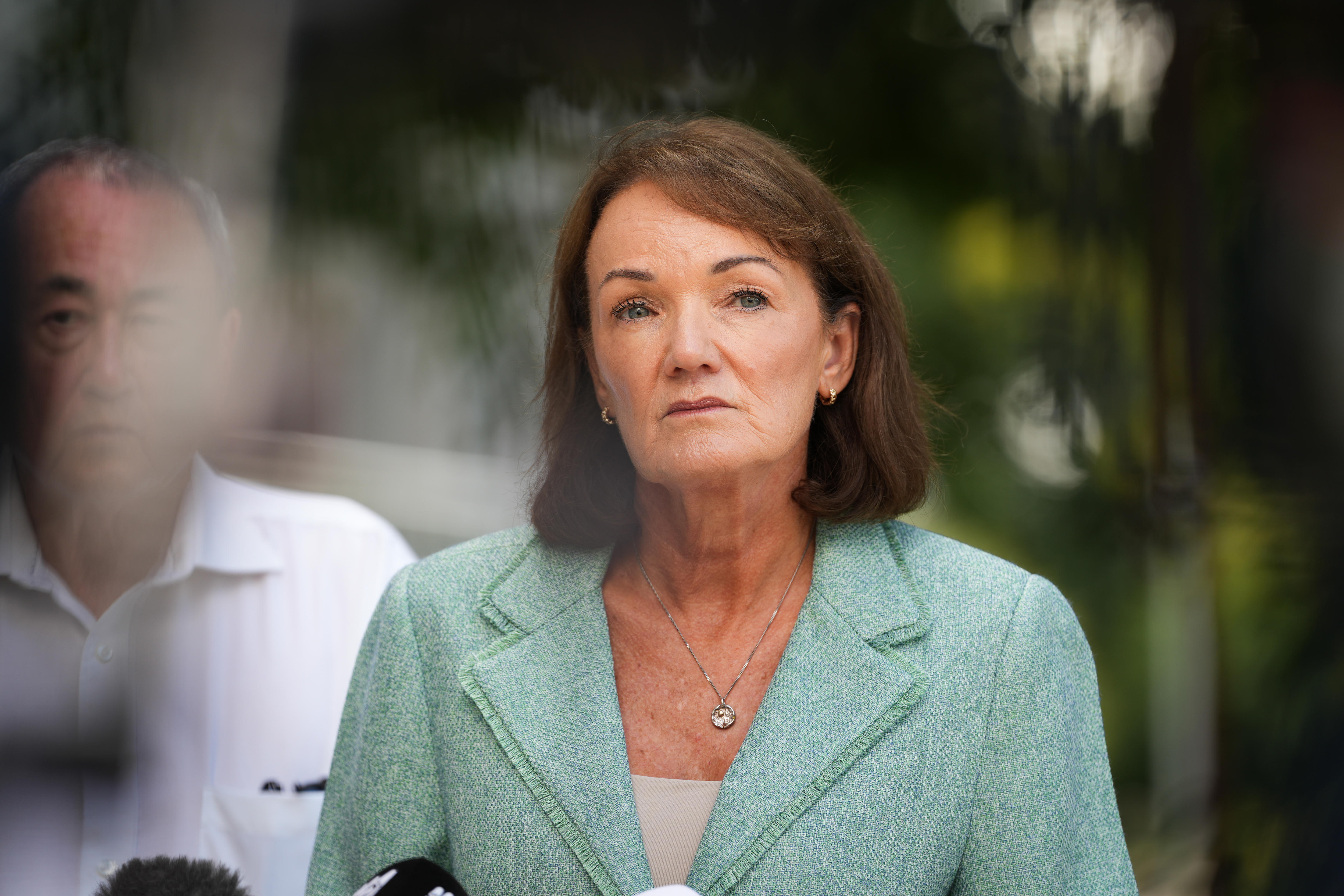 Karen Webb wearing a green jacket looks ahead with a serious expression