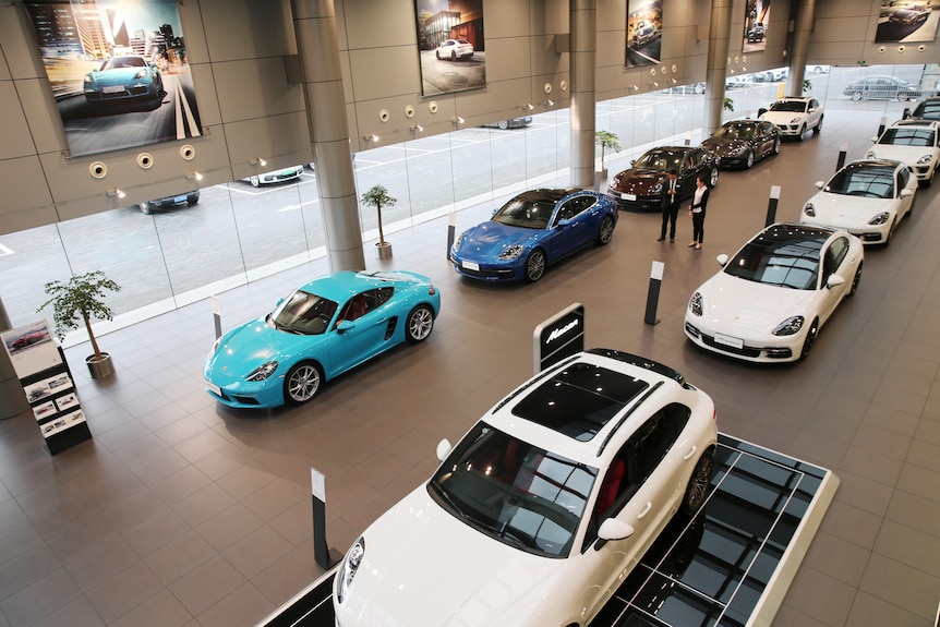 A showroom with two rows of Porsche cars on display 