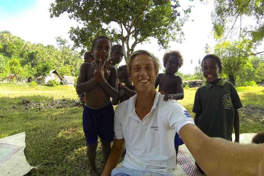 Nicholas Banfield poses for a selfie with local children in Vanuatu