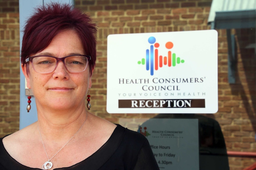 Pip Brennan standing alongside a Health Consumers' Council sign.