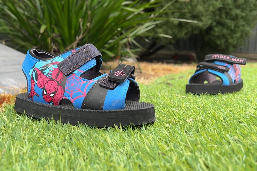 A child's Spider Man sandals on synthetic turf.