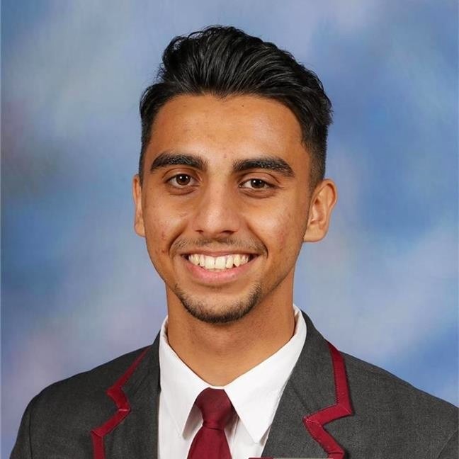 A school photograph or a young man with black hair and a grey and maroon blazer.
