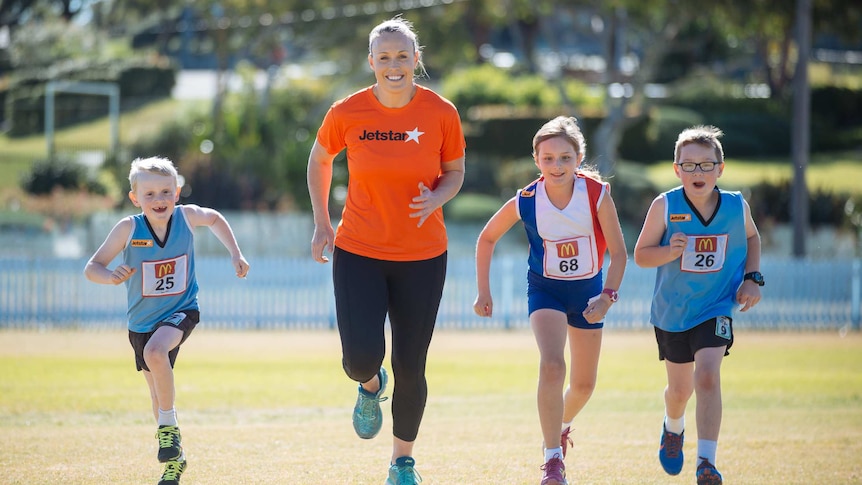Kim Green runs with Little Athletics competitors
