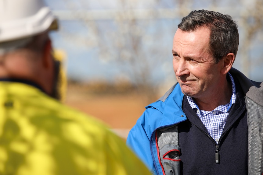 WA premier Mark McGowan stands chatting to a man in high-vis work wear 