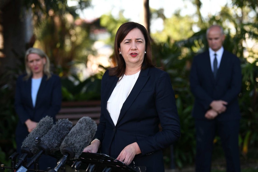 Queensland Premier Annastacia Palaszczuk speaks in front of microphones.