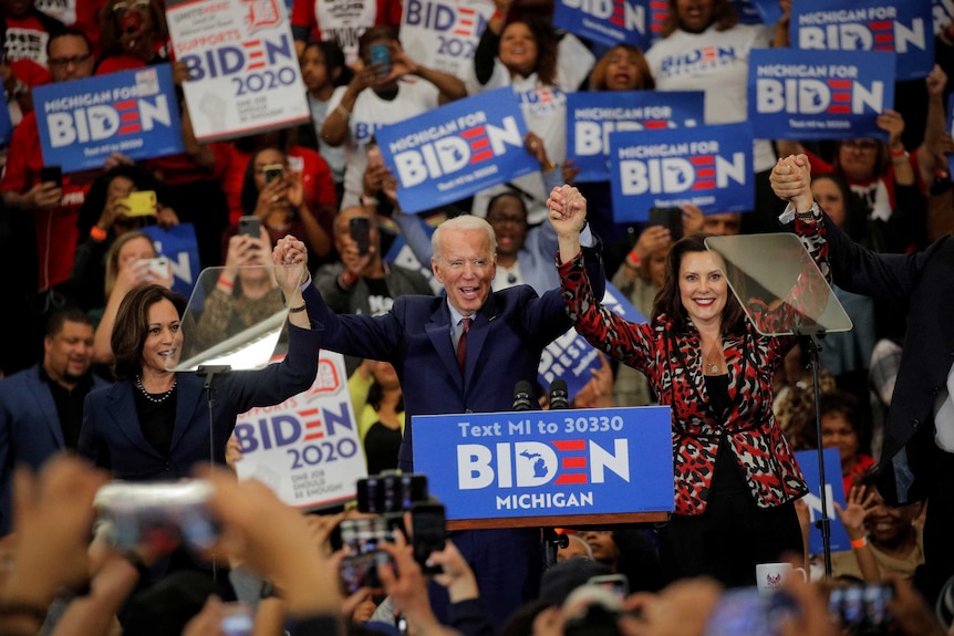 Kamala Harris, Joe Biden and Gretchen Whitmer hold hands and cheers on stage